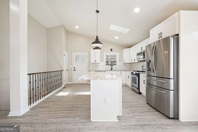 kitchen with a skylight, light wood-style floors, white cabinets, and stainless steel appliances