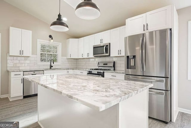 kitchen with a sink, tasteful backsplash, white cabinetry, appliances with stainless steel finishes, and vaulted ceiling