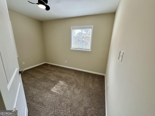 empty room with dark colored carpet and baseboards