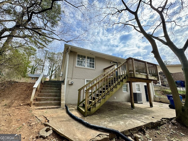 rear view of house with cooling unit, a patio, brick siding, and stairs