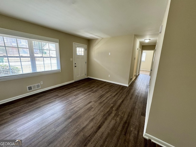 foyer with dark wood-type flooring, baseboards, and visible vents