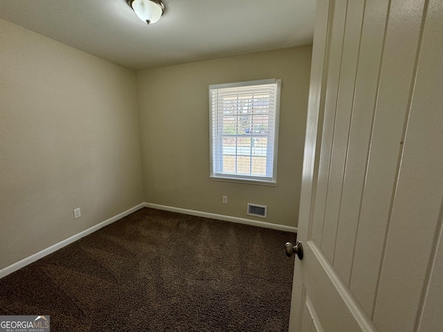 empty room featuring visible vents, baseboards, and dark carpet