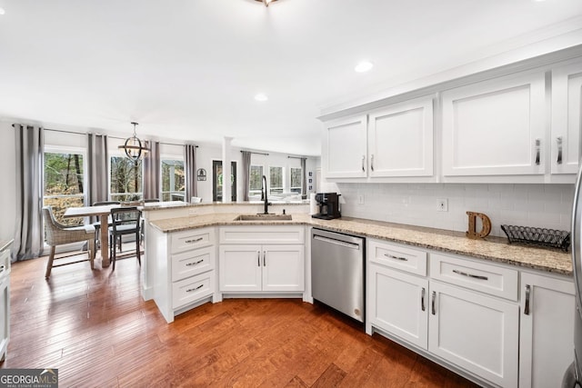 kitchen featuring stainless steel dishwasher, a peninsula, tasteful backsplash, and a sink