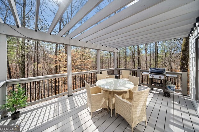 deck featuring outdoor dining area, a view of trees, a pergola, and a grill