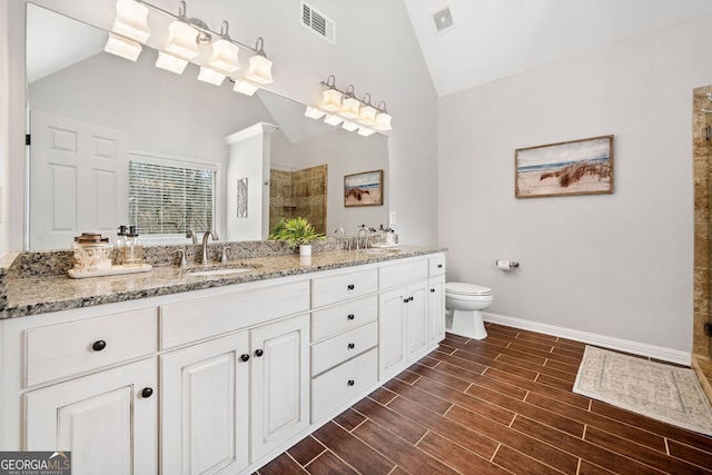 bathroom featuring visible vents, a sink, tiled shower, wood tiled floor, and vaulted ceiling