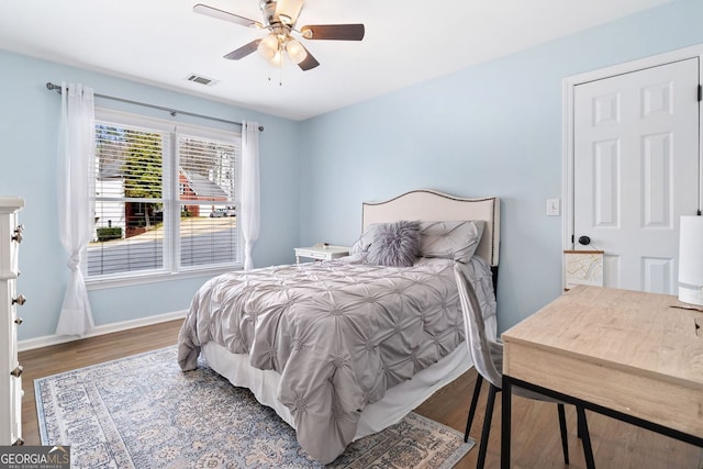 bedroom featuring ceiling fan, visible vents, baseboards, and wood finished floors