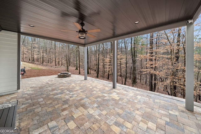 view of patio / terrace with a view of trees, ceiling fan, and an outdoor fire pit