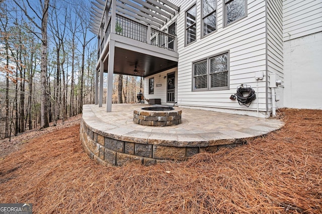 view of patio featuring a fire pit, ceiling fan, and a balcony