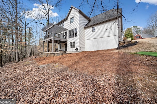 back of property featuring a wooden deck, a patio, and a pergola