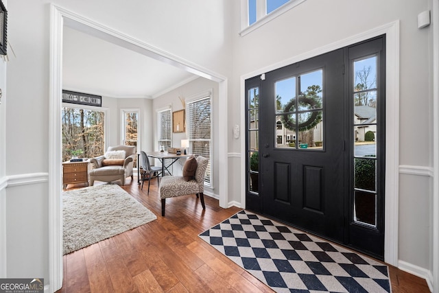 entrance foyer with baseboards, a towering ceiling, crown molding, and hardwood / wood-style flooring