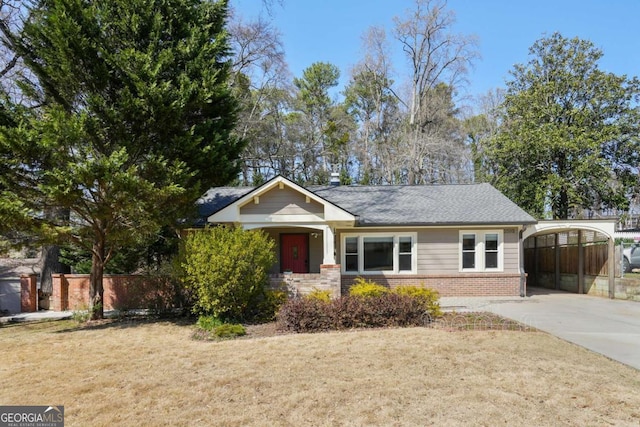 view of front of property with brick siding, a front lawn, fence, concrete driveway, and a carport