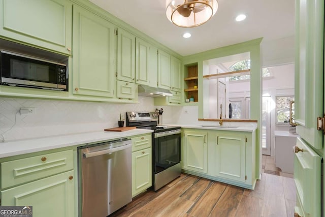 kitchen featuring under cabinet range hood, stainless steel appliances, green cabinets, and a sink