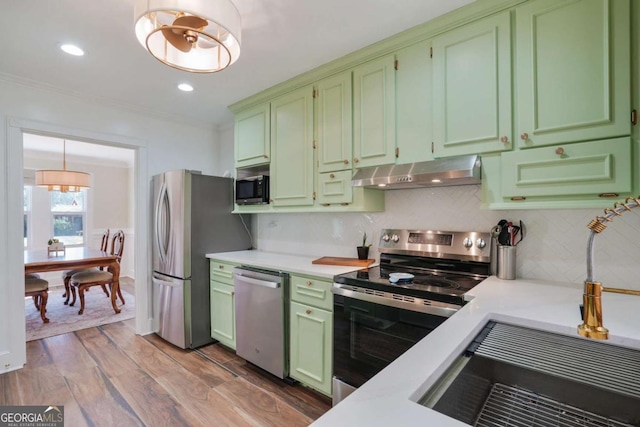 kitchen featuring range hood, light countertops, green cabinetry, and stainless steel appliances