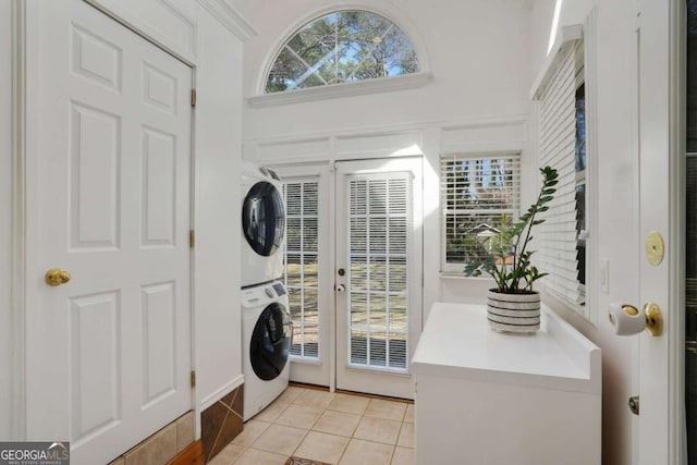 laundry room featuring stacked washer / dryer, laundry area, french doors, a towering ceiling, and light tile patterned flooring