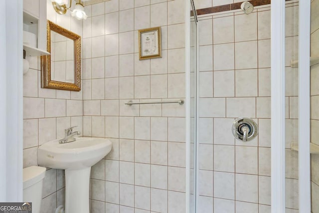 full bath featuring a stall shower, toilet, and tile walls