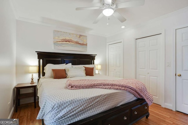 bedroom featuring crown molding, wood finished floors, and multiple closets