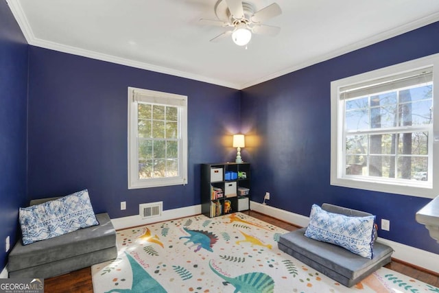 sitting room with visible vents, a ceiling fan, baseboards, and ornamental molding