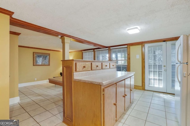 kitchen with a textured ceiling, freestanding refrigerator, light tile patterned flooring, crown molding, and light countertops