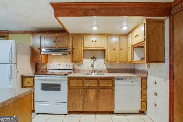 kitchen with tasteful backsplash, light countertops, range hood, white appliances, and a sink