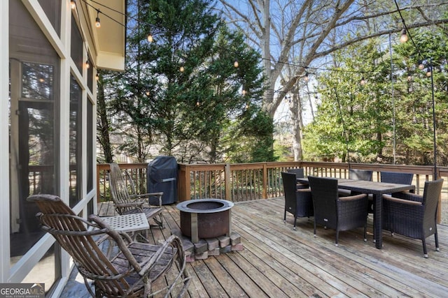 wooden terrace with grilling area, outdoor dining space, and an outdoor fire pit