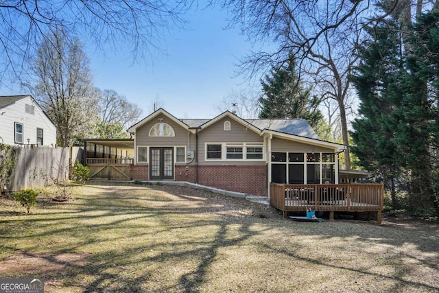 view of front of house featuring fence, a wooden deck, a sunroom, french doors, and brick siding