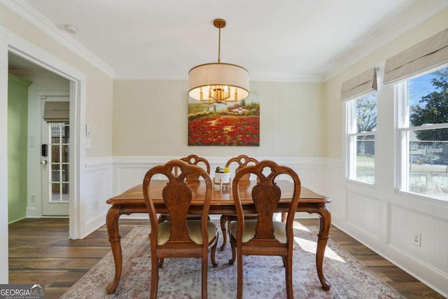 dining space with wainscoting, dark wood finished floors, crown molding, and a decorative wall