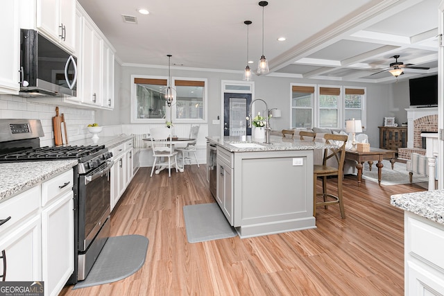 kitchen with visible vents, backsplash, ceiling fan with notable chandelier, stainless steel appliances, and a sink