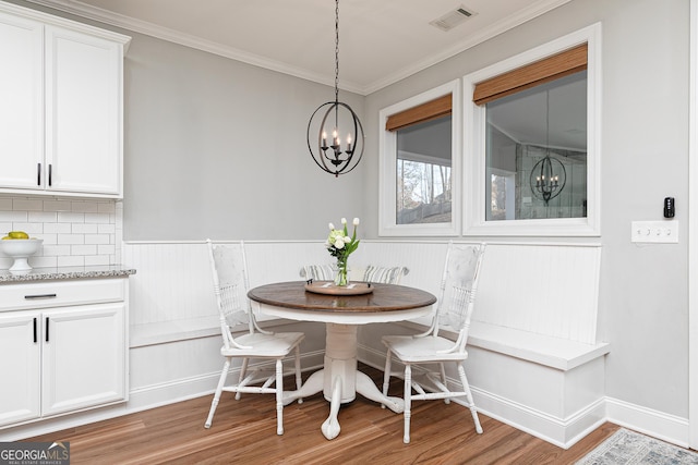 dining area featuring visible vents, light wood finished floors, breakfast area, crown molding, and a chandelier