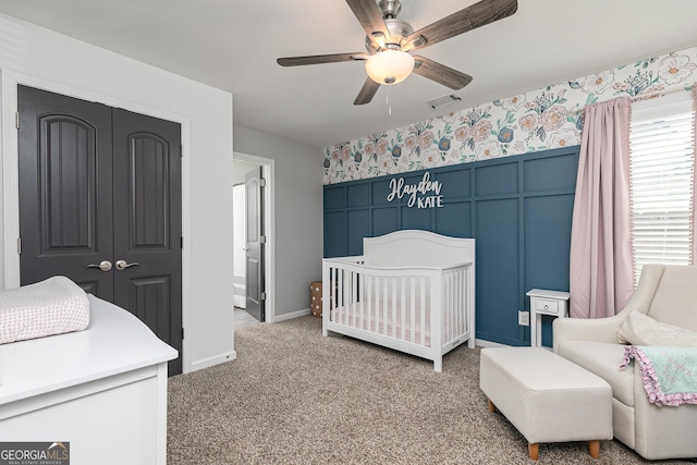 bedroom with visible vents, wallpapered walls, a crib, a closet, and light colored carpet