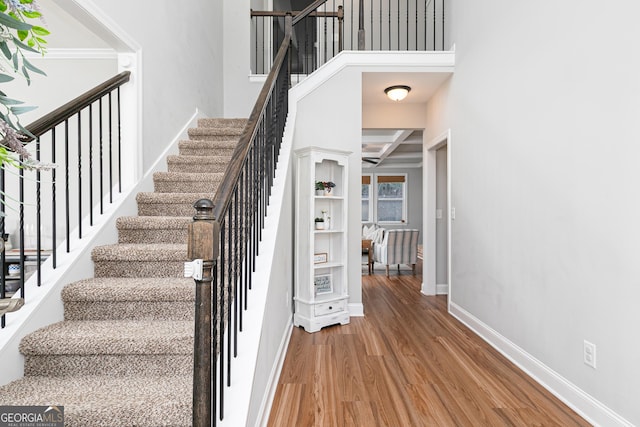 stairs featuring beamed ceiling, baseboards, coffered ceiling, and wood finished floors