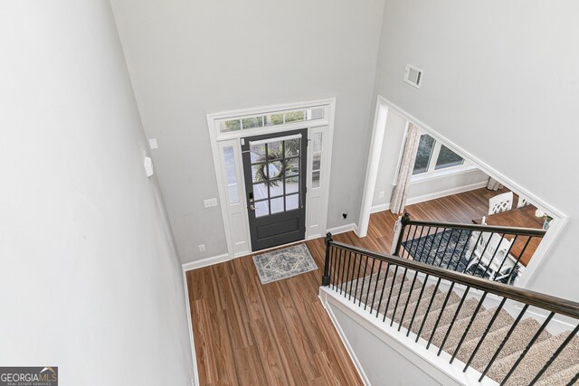 foyer with visible vents, wood finished floors, baseboards, and a towering ceiling