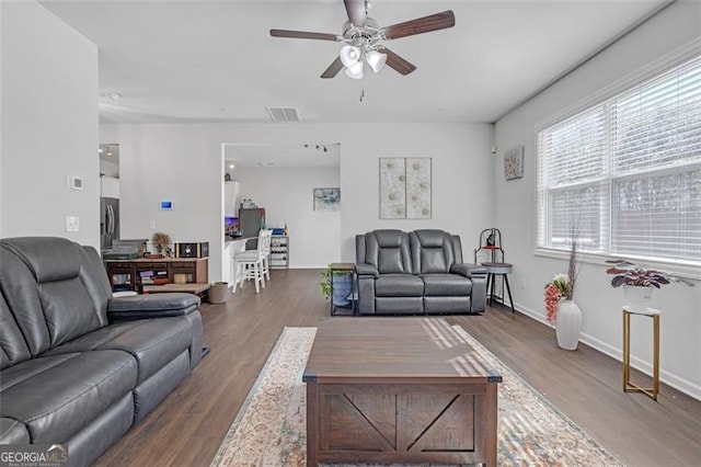 living area featuring visible vents, a ceiling fan, baseboards, and wood finished floors