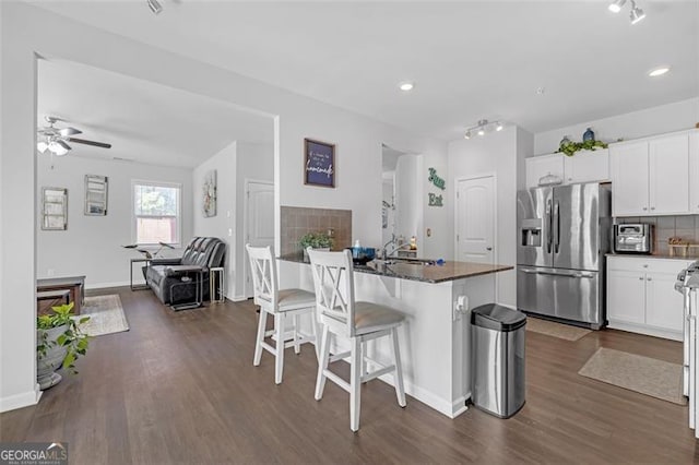 kitchen with dark wood finished floors, a breakfast bar area, tasteful backsplash, and stainless steel fridge