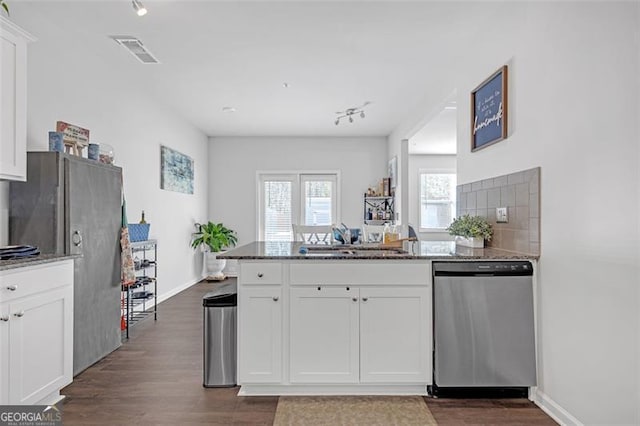 kitchen featuring dishwasher, a peninsula, white cabinets, and a sink