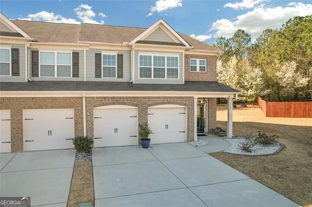 view of front facade featuring brick siding, driveway, an attached garage, and fence