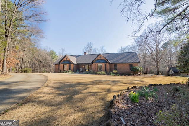 view of front of house with a front yard, brick siding, and a chimney