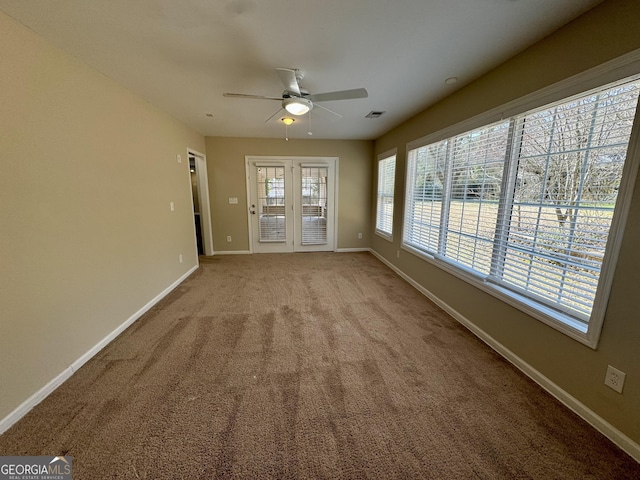 carpeted spare room with visible vents, baseboards, and ceiling fan