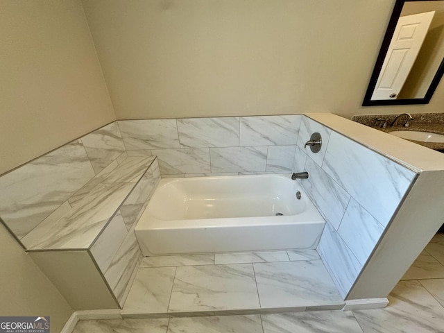 bathroom featuring a sink, marble finish floor, and a bath