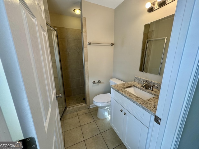 bathroom featuring tile patterned floors, toilet, a stall shower, and vanity