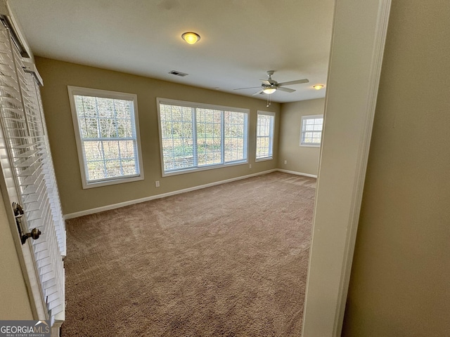 empty room featuring carpet flooring, baseboards, visible vents, and ceiling fan