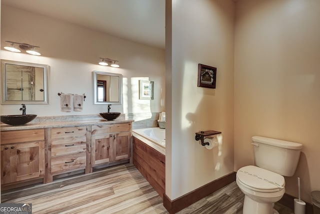 full bath featuring a bath, wood finished floors, toilet, and a sink