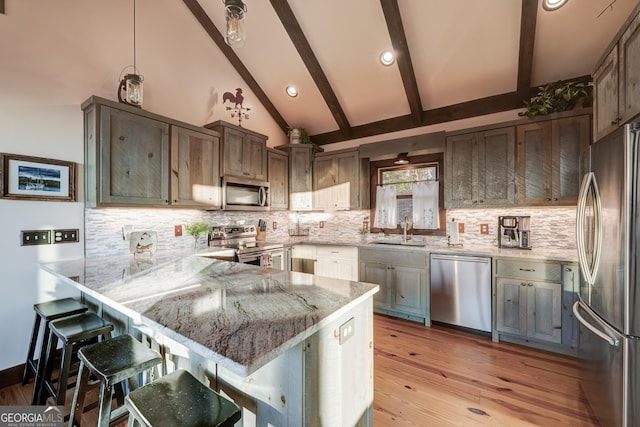 kitchen featuring light stone countertops, a peninsula, lofted ceiling with beams, a sink, and stainless steel appliances