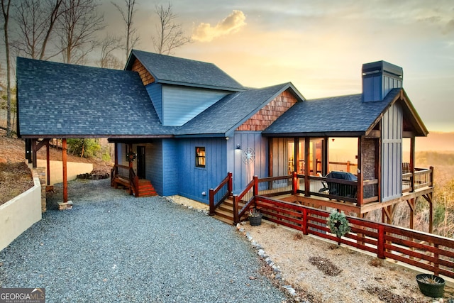 view of front of house with a chimney, board and batten siding, roof with shingles, and driveway