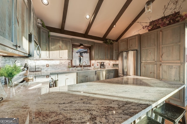 kitchen with vaulted ceiling with beams, light stone countertops, decorative backsplash, appliances with stainless steel finishes, and a sink