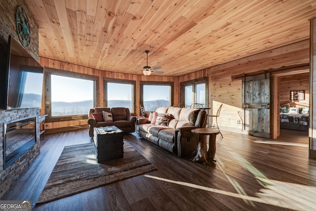 living area featuring a stone fireplace, wooden ceiling, and wood finished floors