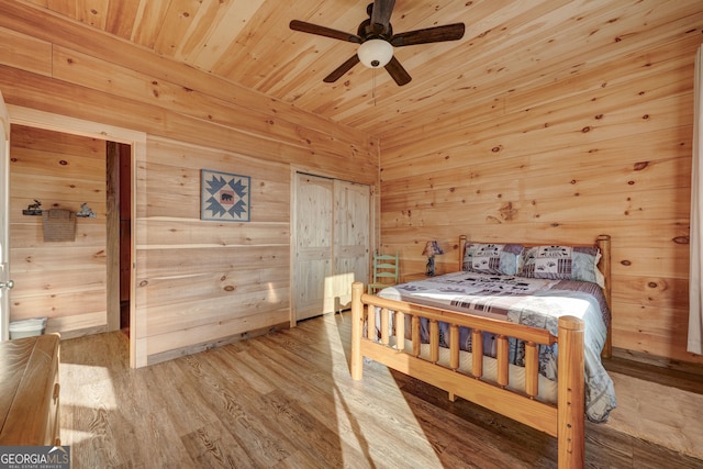 bedroom with a ceiling fan, ensuite bath, wood finished floors, wooden ceiling, and wood walls