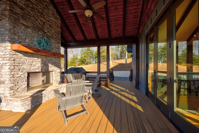 wooden terrace with grilling area and an outdoor stone fireplace