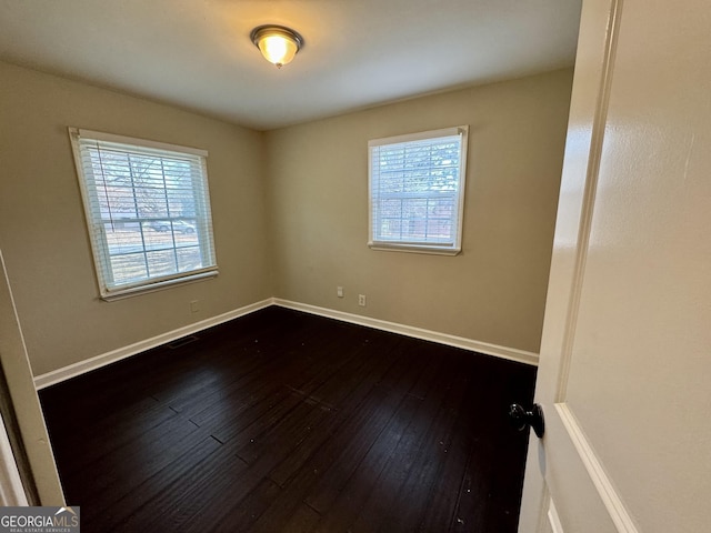 empty room with visible vents, baseboards, and dark wood-style floors