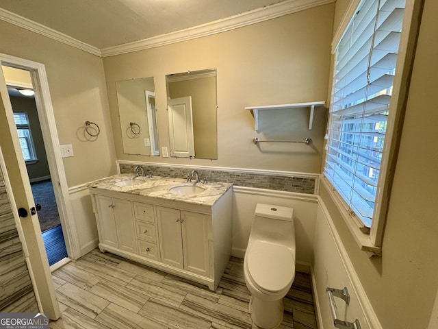 bathroom with ornamental molding, toilet, a wealth of natural light, and a sink