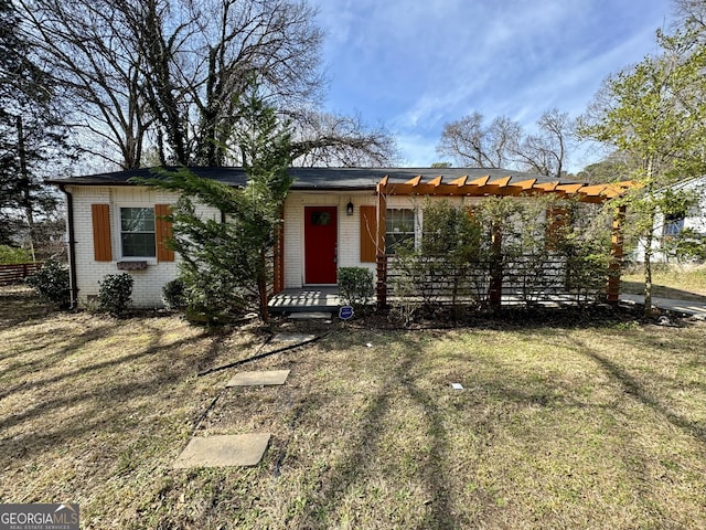 single story home with a front lawn, brick siding, and a pergola